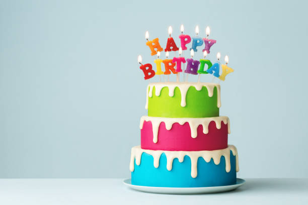 お誕生日おめでとうキャンドルとカラフルな段になったバースデーケーキ