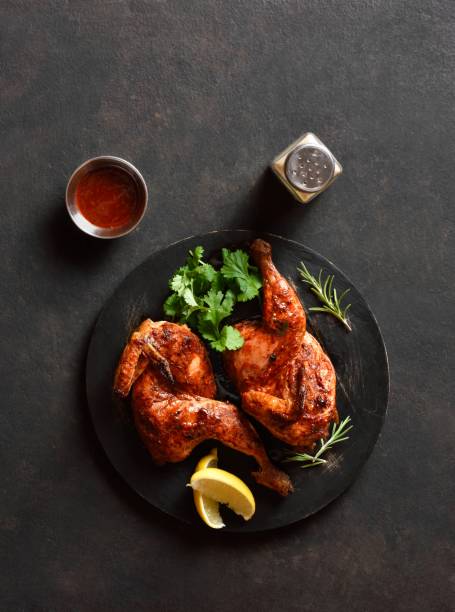 istock Roasted half chicken on black wooden board. Top view 2017822523