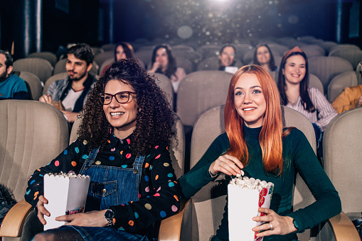 Group of people enjoying movie theater during movie premiere. They are happy and smiled.