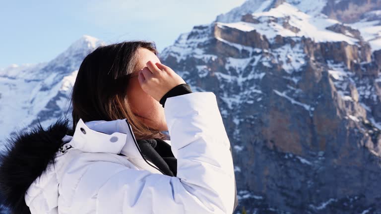 Short brown hair woman in white winter coat put sunglasses at Switzerland Alps