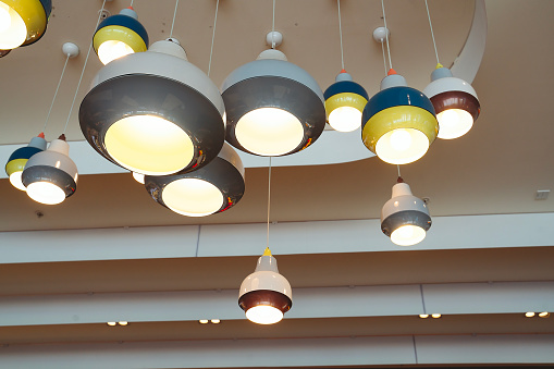 Classic lighting bulbs are glowing in orange warming shade, there are hanging from ceiling for Interior cozy style decoration. Close-up and selective focus.