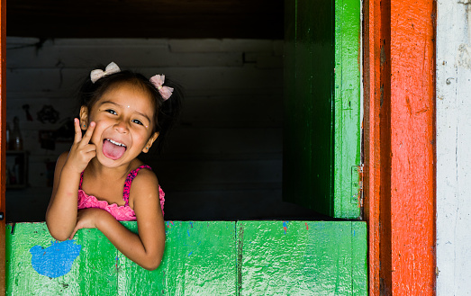 portrait of an indigenous girl playing with her hands and making gestures with her face of happiness.