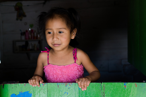 indigenous girl from colombia standing looking out of the window in concentration