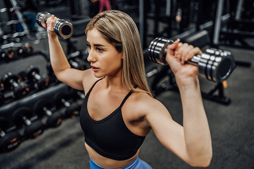 Young woman practicing with dumbbells in the gym