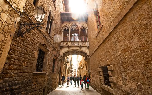 Barcelona, Spain - 16 April, 2023: Bishop's Bridge (El Pont del Bisbe) in Barri Gotic quarter, iconic place in Barcelona city. People walking down the street.