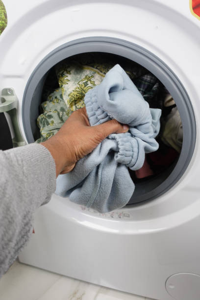 istock man putting shirt into washing machine. 2017900535