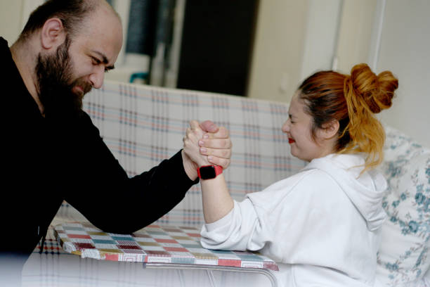 istock Young happy couple having fun while arm wrestling at home 2017907489