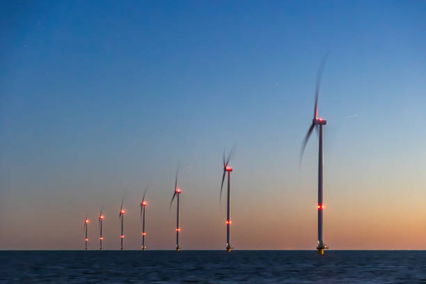 Off shore wind turbines or wind mills at sea at blue dusk or night , long exposure and stars visible. High quality photo