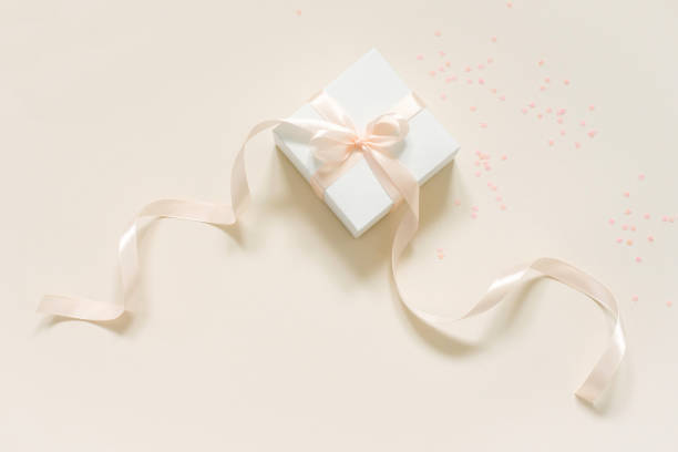 istock Gift box with a satin ribbon and bow on a beige background 2017955406