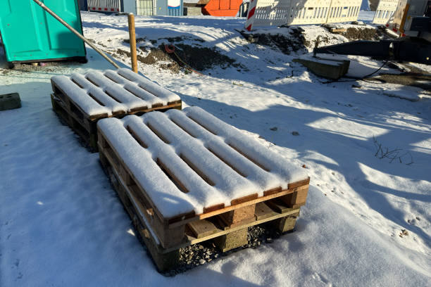 Wooden pallets covered with snow lie on a construction site.