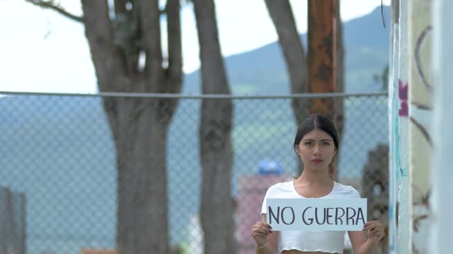 Woman holding No war sign in spanish, No guerra demanding to stop