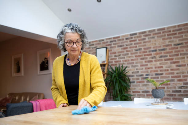 mulher madura limpando uma superfície de cozinha doméstica - cleaning domestic kitchen counter top housework - fotografias e filmes do acervo