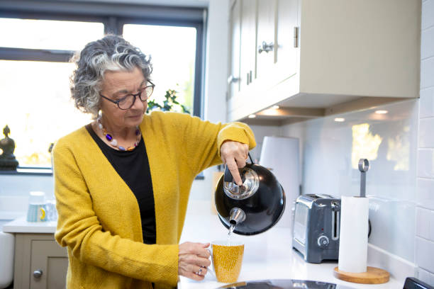 Mature woman making a hot drink in a domestic kitchen