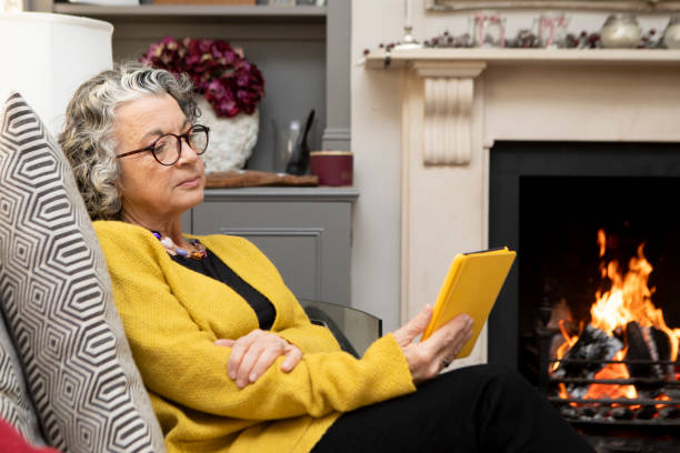 istock Mature woman sitting on a sofa and reading an e-reader 2018019460