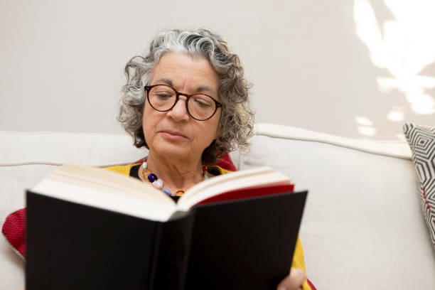 istock Mature woman sitting on a sofa and reading a book 2018019766