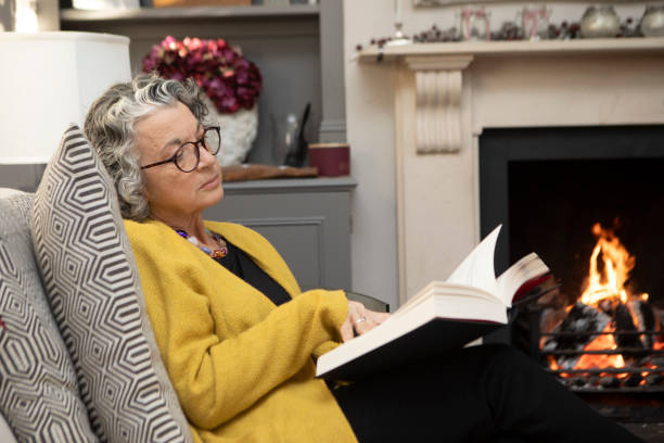 istock Mature woman sitting on a sofa and reading a book 2018021348