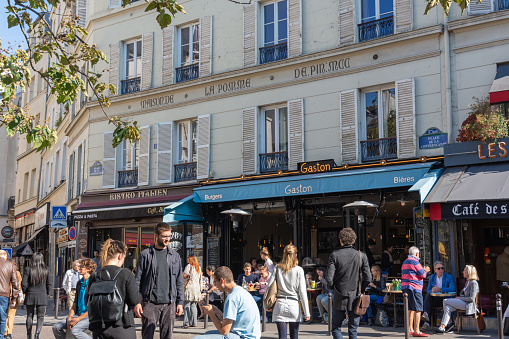 Paris, France - October 8, 2018. The Place de la Contrescarpe on rue Mouffetard is surrounded by cafes and is popular with tourists and locals. Building facades include historical markers.