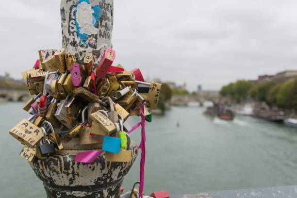Paris, France - October 2, 2018 - There are love locks all over the city of Paris. This lamp post is covered with colorful locks that stand out on a gray day.