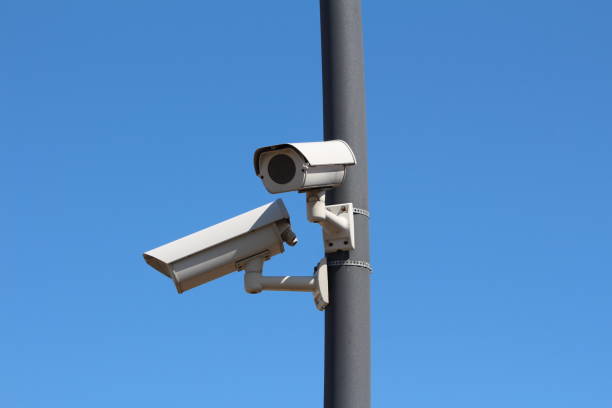 istock Two small fake dummy modern white closed circuit TV CCTV security cameras looking in opposite directions mounted on dark grey metal pole 2018041378