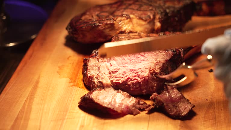 Chef or Waiter Slices Cooked Meat with Knife - Culinary Professional Prepares Savory Dish - Cooking, Culinary Arts, and Food Service Concept - Precision and Skill in Meat Preparation