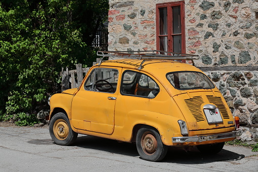 Vevcani, N.Macedonia-April 20, 2019: Classical orange-yellow Zastava 750 LE car from the former Yugoslav communist era parked by a local house at the beginning of the trail going to the local springs.