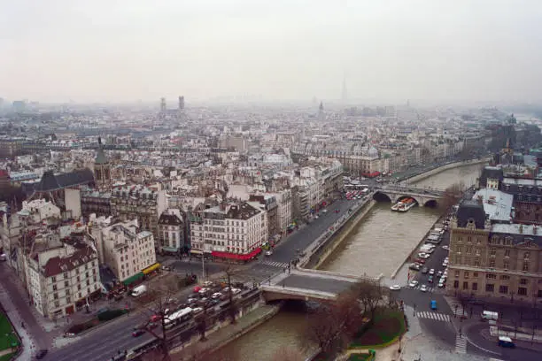 Grainy film photograph of foggy buildings streets and river in historic Paris France.