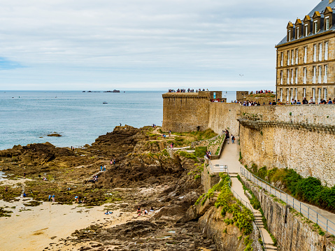 Tourists enjoying the beach surrounding the fortress of Saint Malo during low tide, Brittany, France