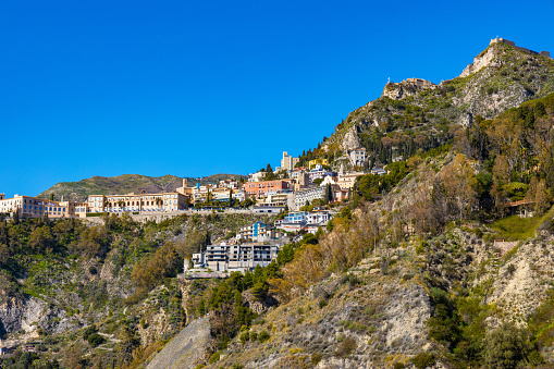 Taormina, Sicily, Italy - February 15, 2023: Panoramic view of Taormina shore at Ionian sea with Castello Saraceno castle, Giardini Naxos and Villagonia towns in Messina region