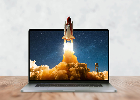 Laptop on the desktop and the space shuttle rocket successfully takes off beyond the frames of display. Start up and success, creative idea. Development, marketing and application, Concept