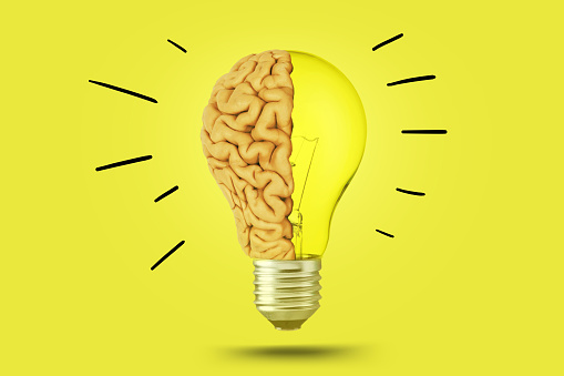 Creative brain light bulb shining on bright yellow color background, concept. Think differently, creative idea. Brainstorm