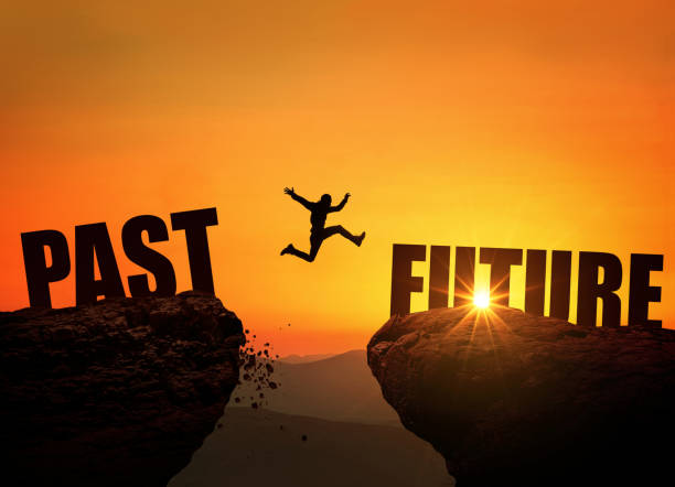 istock Successful man jumps over a cliff with the text Future at sunset, concept. Leap from past to future, creative idea. Rock at sunrise 2018099186