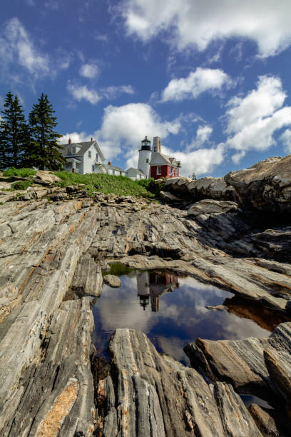 pemaquid point lighthouse and bell tower reflection in puddle on a bright summer day dotted with puffy clouds - maine lighthouse reflection pemaquid point lighthouse imagens e fotografias de stock