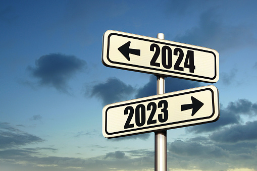 Road signs indicate the path to the new year 2024 and the old year 2023 on a blue sky, creative idea. Choose a new road, concept. Change for the better
