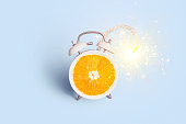 Creative vintage alarm clock orange bomb with wick and sparks on a blue background, concept. Advertising and marketing, creative idea. Vitamin C