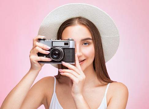 A beautiful, attractive female photographer holds a vintage camera. Tourism and travel concept.