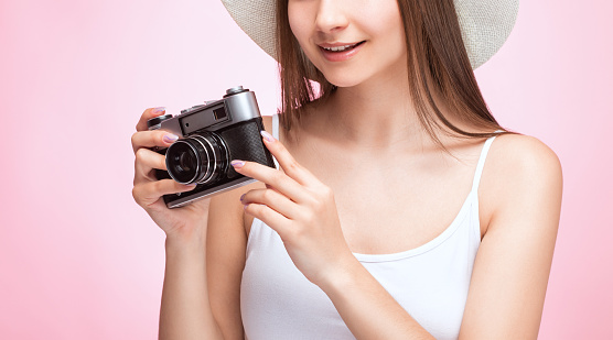 A beautiful, attractive female photographer holds a vintage camera. Tourism and travel concept.