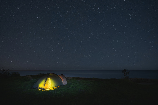 Wild camping with a tent on the shore of the steep Baltic Sea in Paldiski under the starry sky. High quality photo