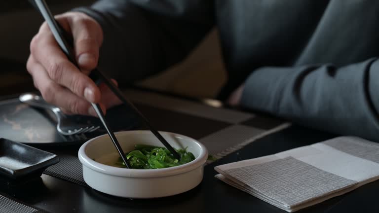 man eating bowl of Wakame seaweed salad.