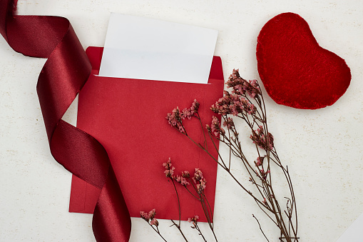 Blank greeting card, flyer or invitation card mockup with Valentines or women's day hearts and gypsophila, red ribbon on grunge background