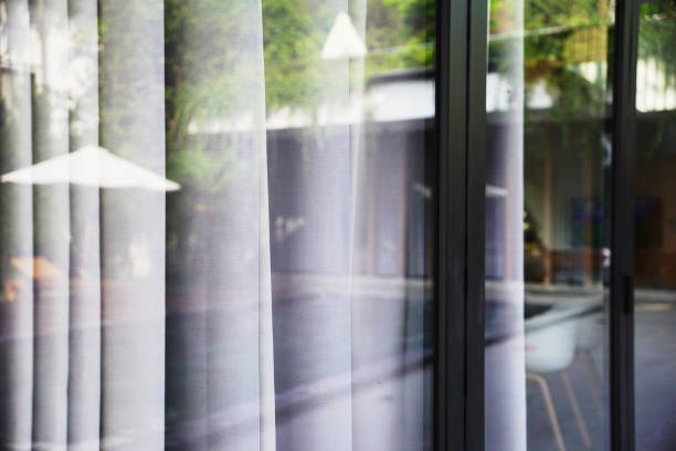 istock Pool reflection on glass door with white curtain in a summer villa 2018161804