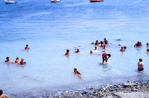 Vulcano Island, Aeolian Islands, Sicily, Italy - August 10, 1980: view of the beach on the island of Vulcano with bathers immersed in the hot sulphurous water, in the Aeolian Islands