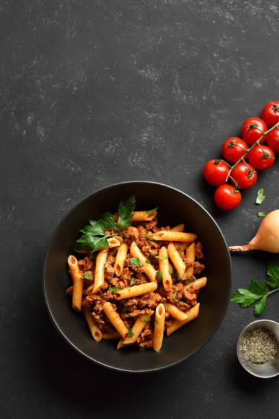 istock Penne pasta with minced meat, tomato sauce and greens, top view 2018196316