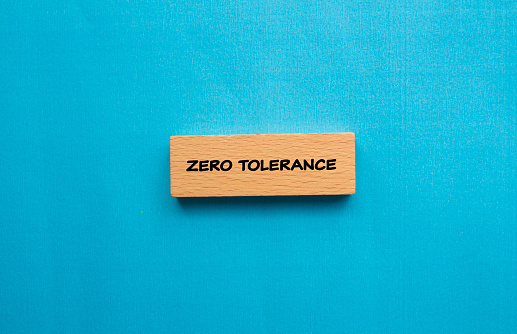 Zero tolerance words written on wooden block with blue background. Conceptual photo. Top view, copy space.