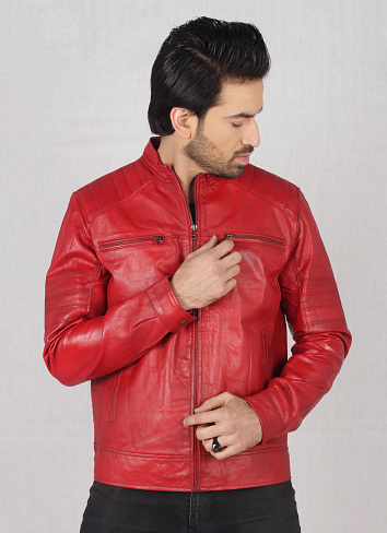 A young stylish male model posing in style with red leather jacket and black top and jeans in white background