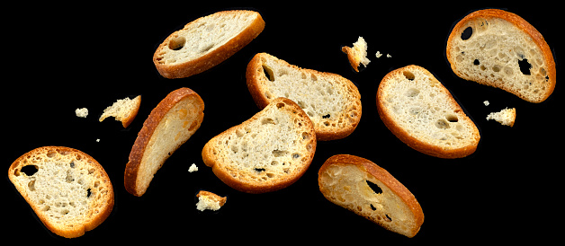 Falling bruschetta crackers, round bread croutons isolated on black background, full depth of field