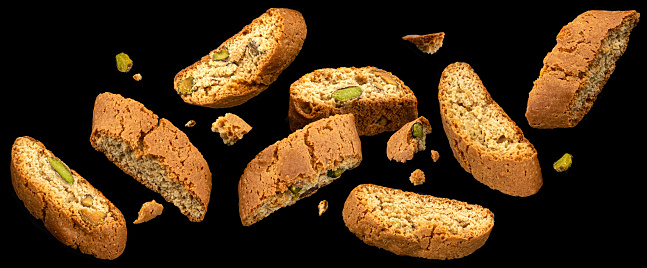 Falling Cantuccini biscuits, Italian almond cookies with pistachio nuts on black background