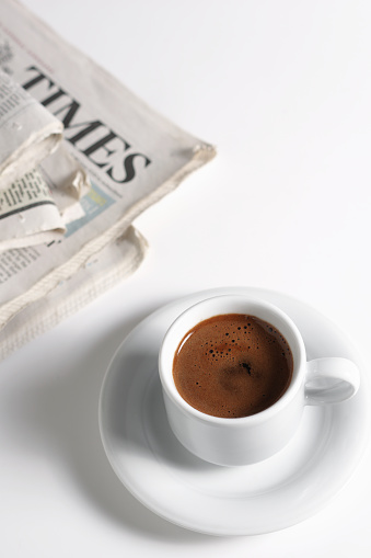 Cup of coffee and newspaper on white background