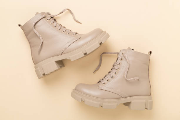 istock Beige trendy boots on color background, top view. 2018382880