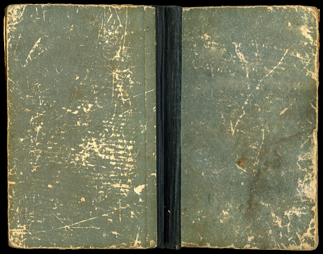 Cover of an old blue book on a black background. The book is unfolded. Side view.