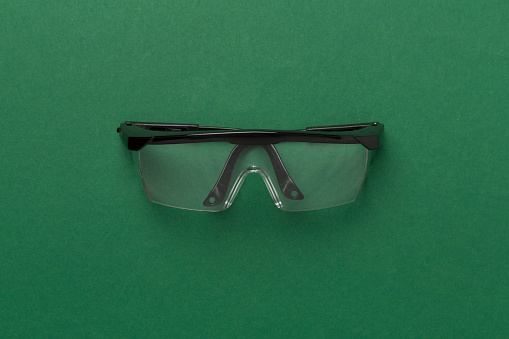 Safety glasses on color background, top view
